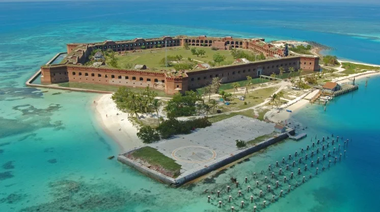 A large brick fort located in the middle of bright blue water.