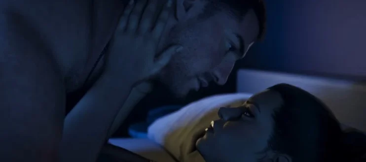 Lucia interacting intimately with Jason in a dimly lit motel room.